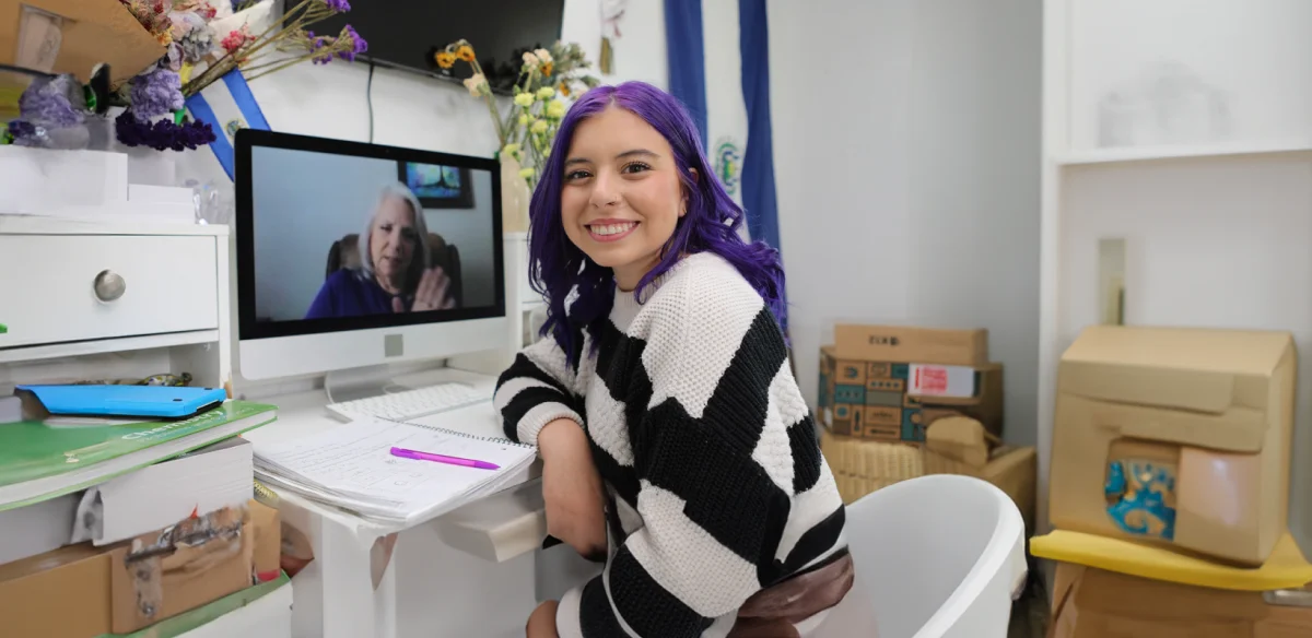 High school student wearing a stripped sweater while attending to an online class at home